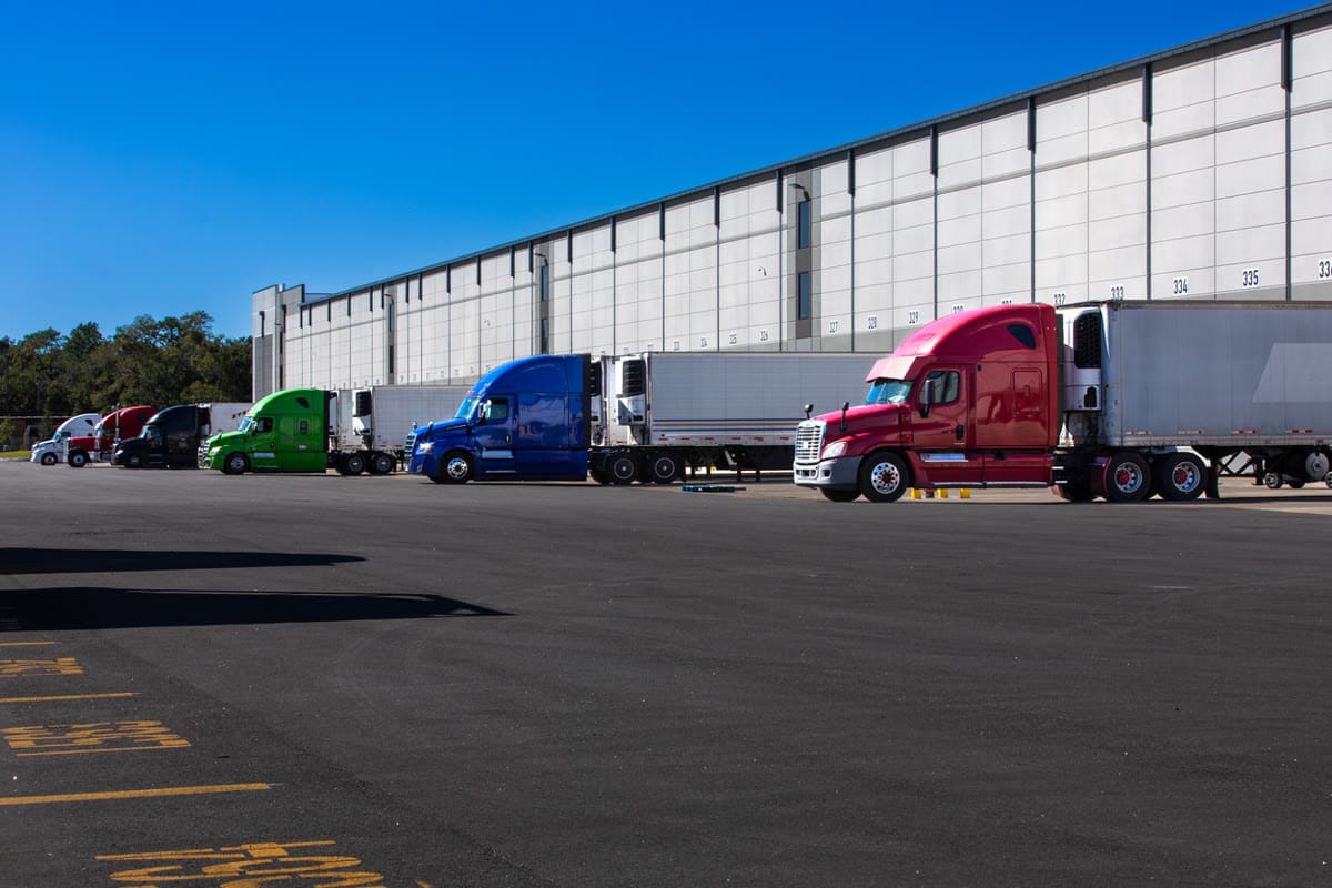 Semi trucks backed onto the numbered bays of a warehouse loading dock