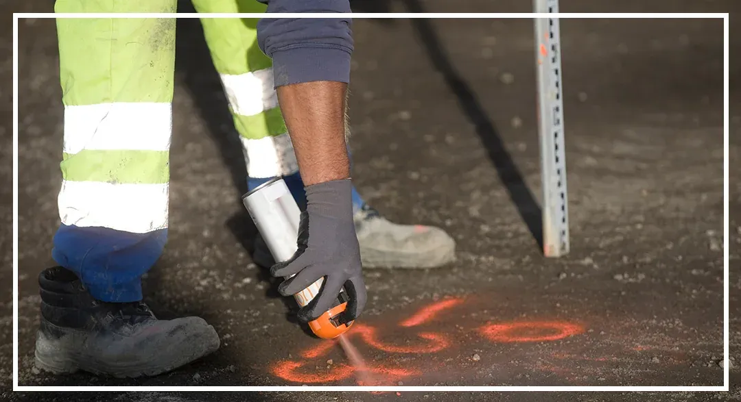 A field worker marking pavement with bright spray paint