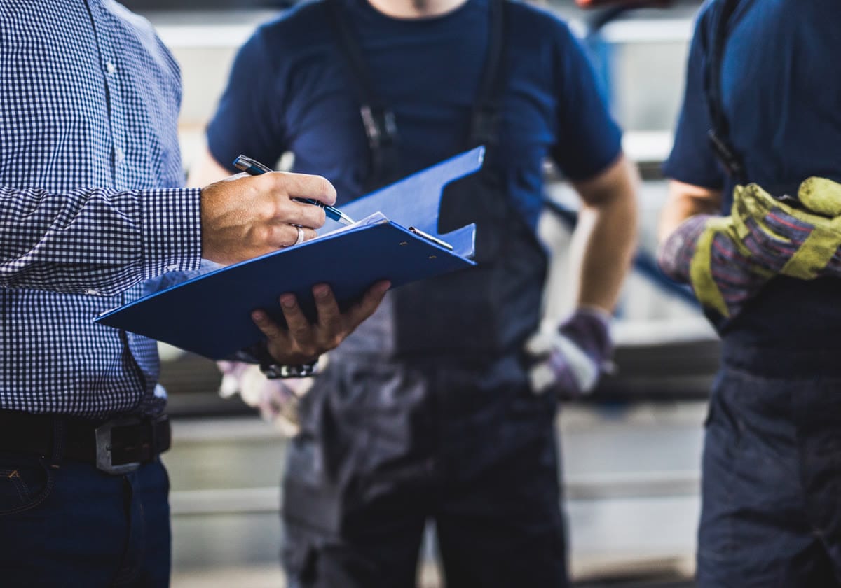 A rep writing an order on a clipboard while two crew members look on